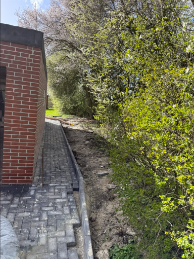 Neu gepflasterter Bereich entlang eines Hauses mit Randsteinen