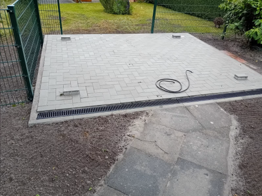 Neu gepflasterte Fläche mit Entwässerungsrinne im Gartenbereich