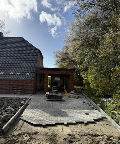 Großflächige Pflasterarbeiten entlang eines Hauses im Bauzustand